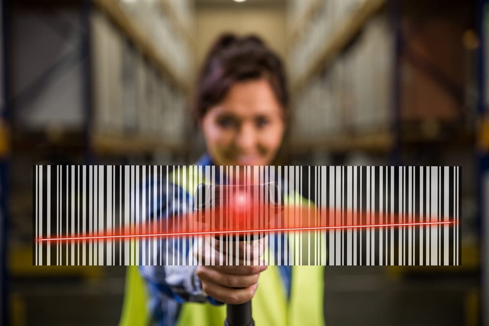 A blurred young woman in a yellow vest scanning a huge barcode in front of her.