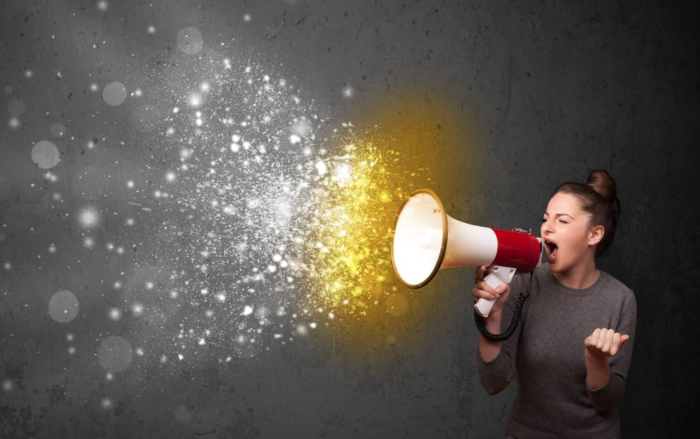 A young woman yelling into a megaphone while sparks burst from it.