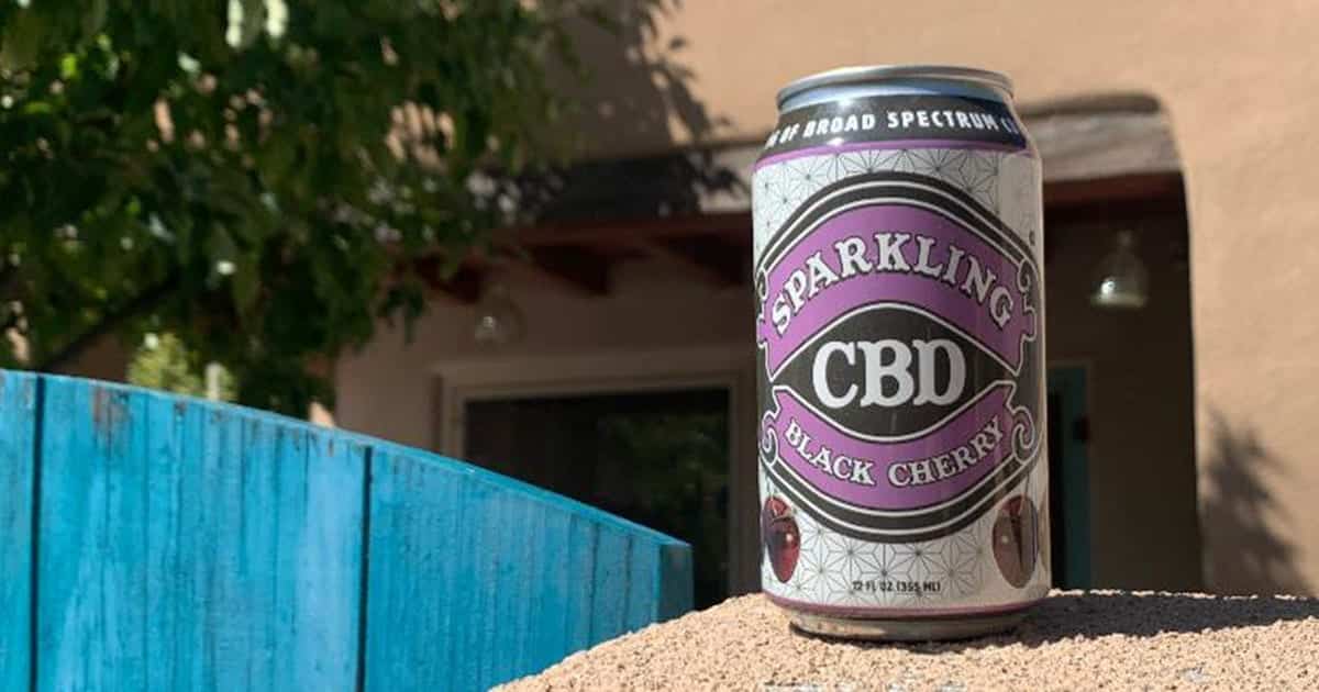 Sparkling CBD Black Cherry shrink sleeve label is sunbathing on a gate wall in front of the house.