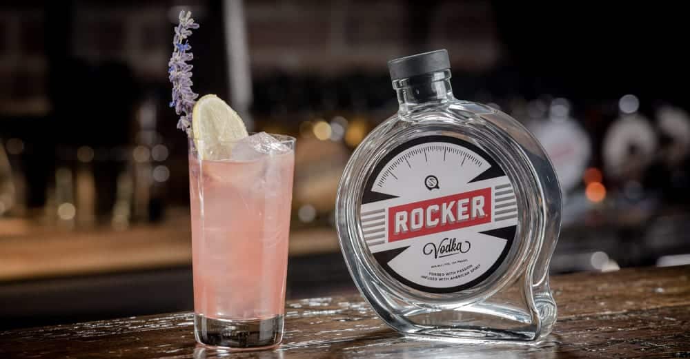 Rocker Vodka bottle and nicely decorated pink cocktail on a wooden counter.