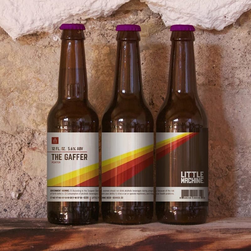Three perfectly labeled bottles of The Gaffer Little Machine beer on a wooden surface.
