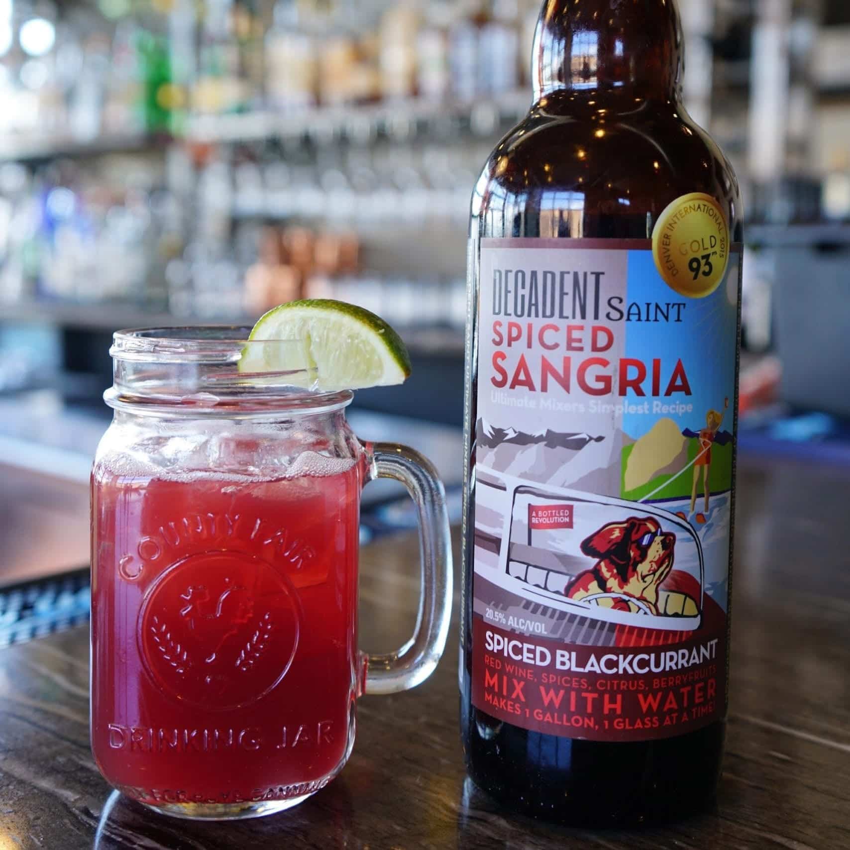 A drinking jar filled with sangria and a bottle of Spiced Sangria decorated with an attractive label.