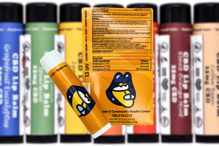 Orange lip balm label created by Columbine Label Company in front of other lip balms.
