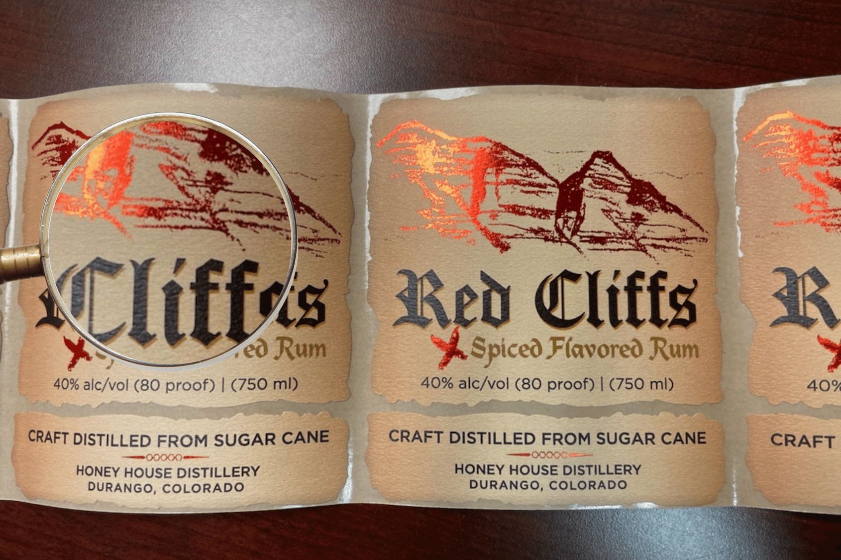 Red Cliffs Spiced Rum vintage textured wine stock labels under magnifying glass.