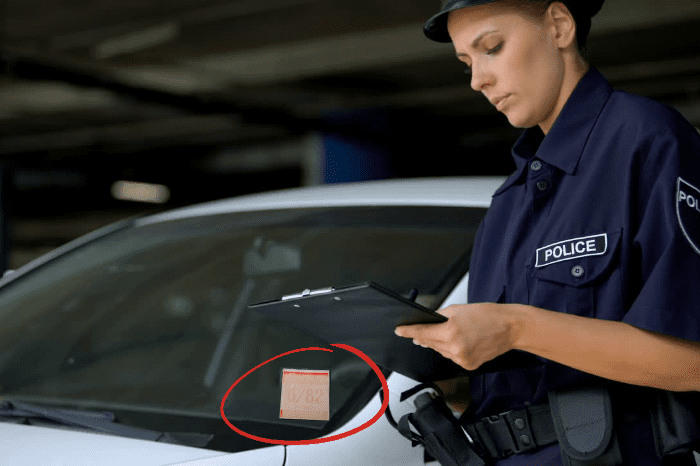 A police officer is checking UV resistant sticker on the windshield of a car.