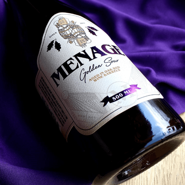 Menage wine 500ml bottle lying on a blue cloth.