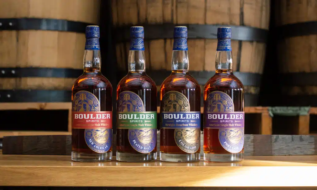 Four bottles of Boulder Whiskey featuring unique hot stamp custom labels designed by Columbine Label.