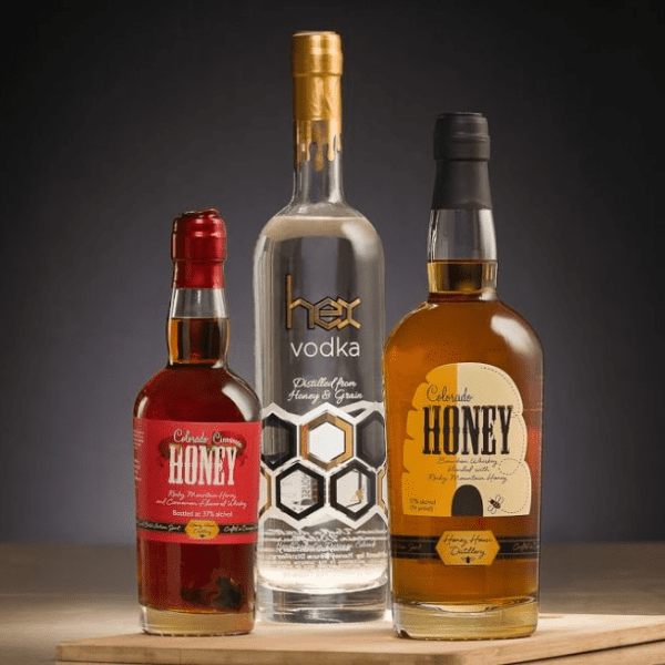 Three bottles of Honeyville spirits products featuring creative labels created by Columbine Label Company.