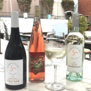 On a bar counter, Carruth Cellars' black, rose, and white wines are displayed with their new custom labels.