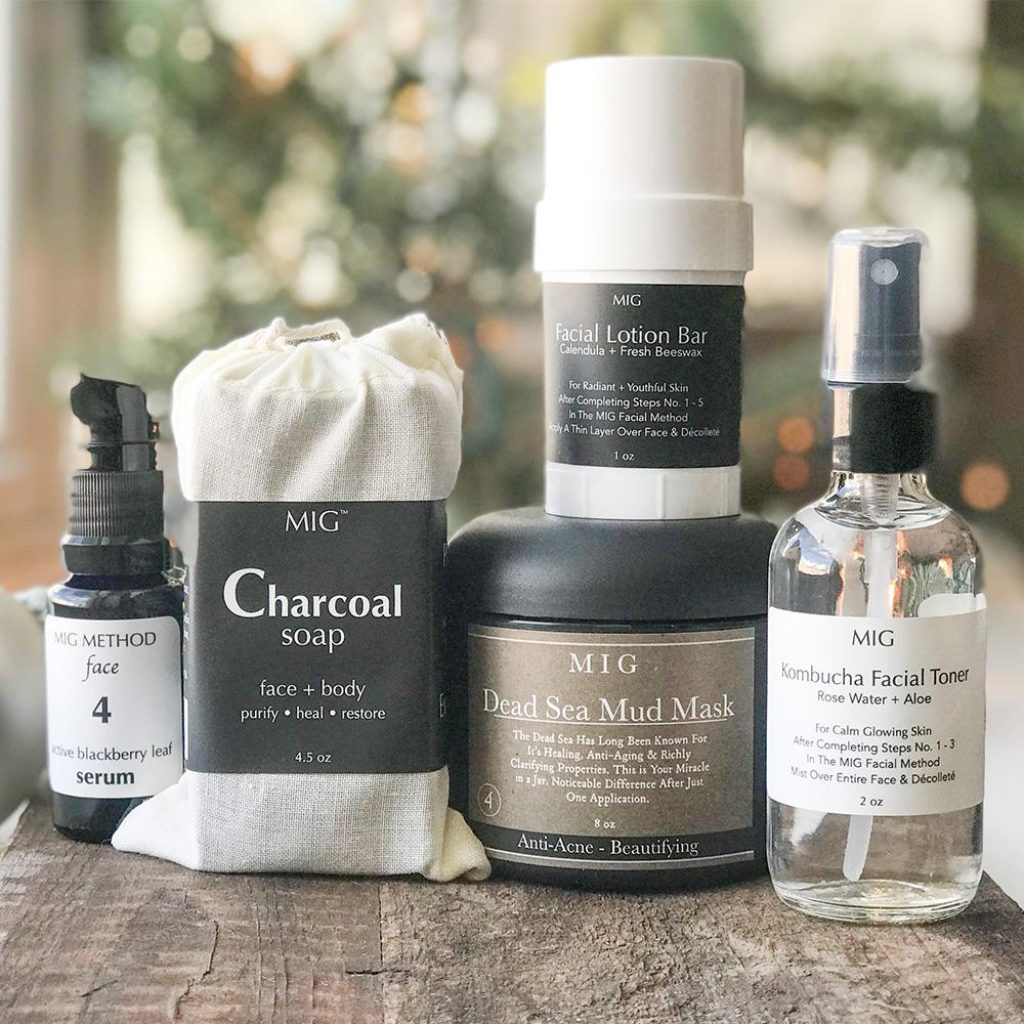 A variety of MIG Soap and Bath care products on a wooden surface presenting their simple but elegant custom labels created by Columbine Label Company.