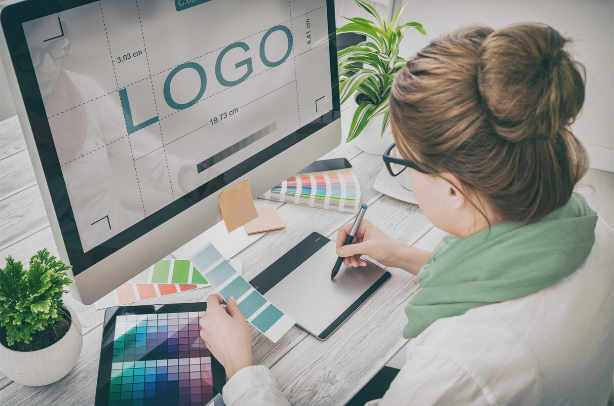 graphic designer sitting at their desk, preparing a custom product label and logo, perhaps for a customer of Columbine Label Company.